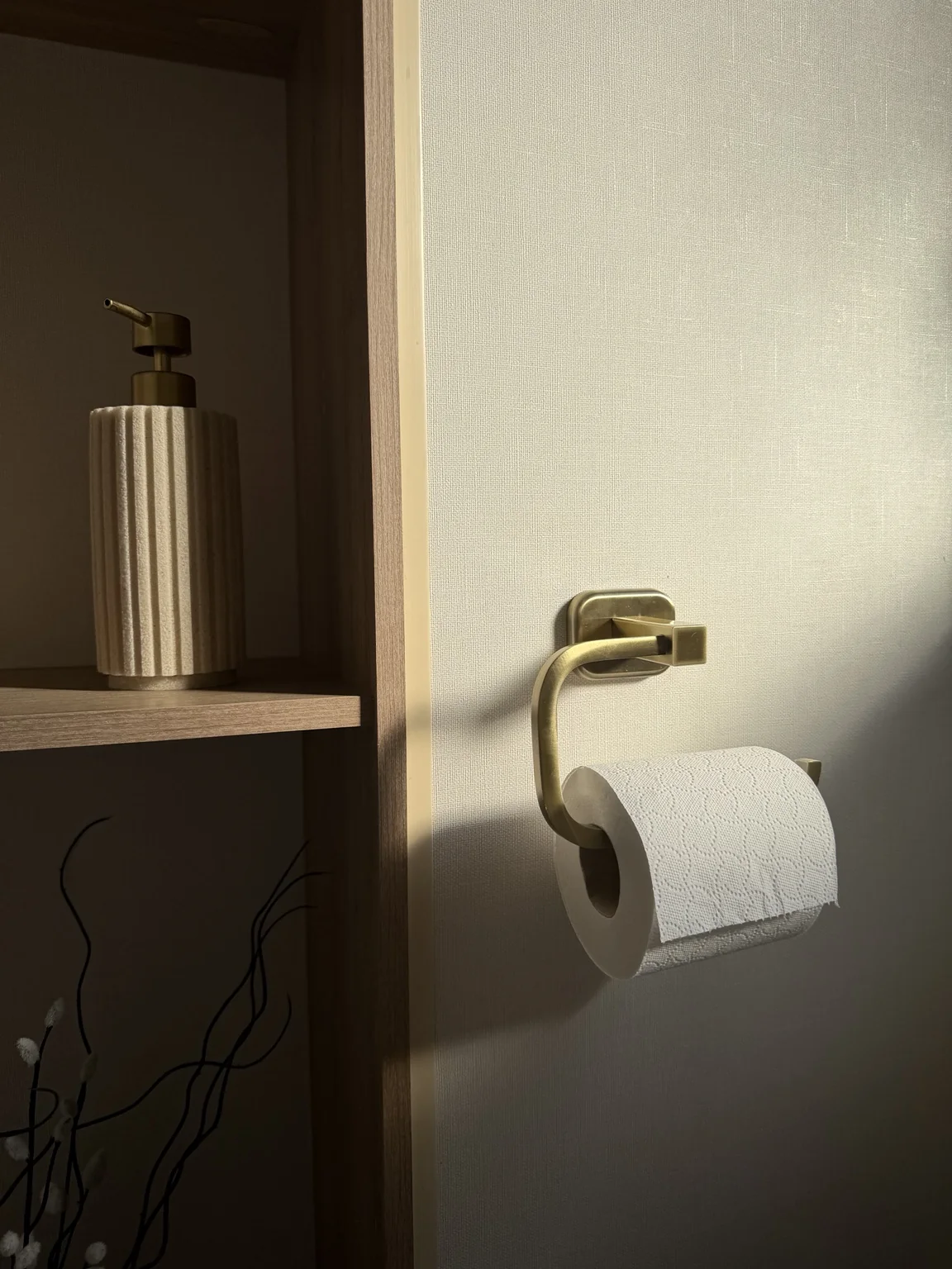 Thoughtful bathroom details with brass toilet roll holder and soap dispenser