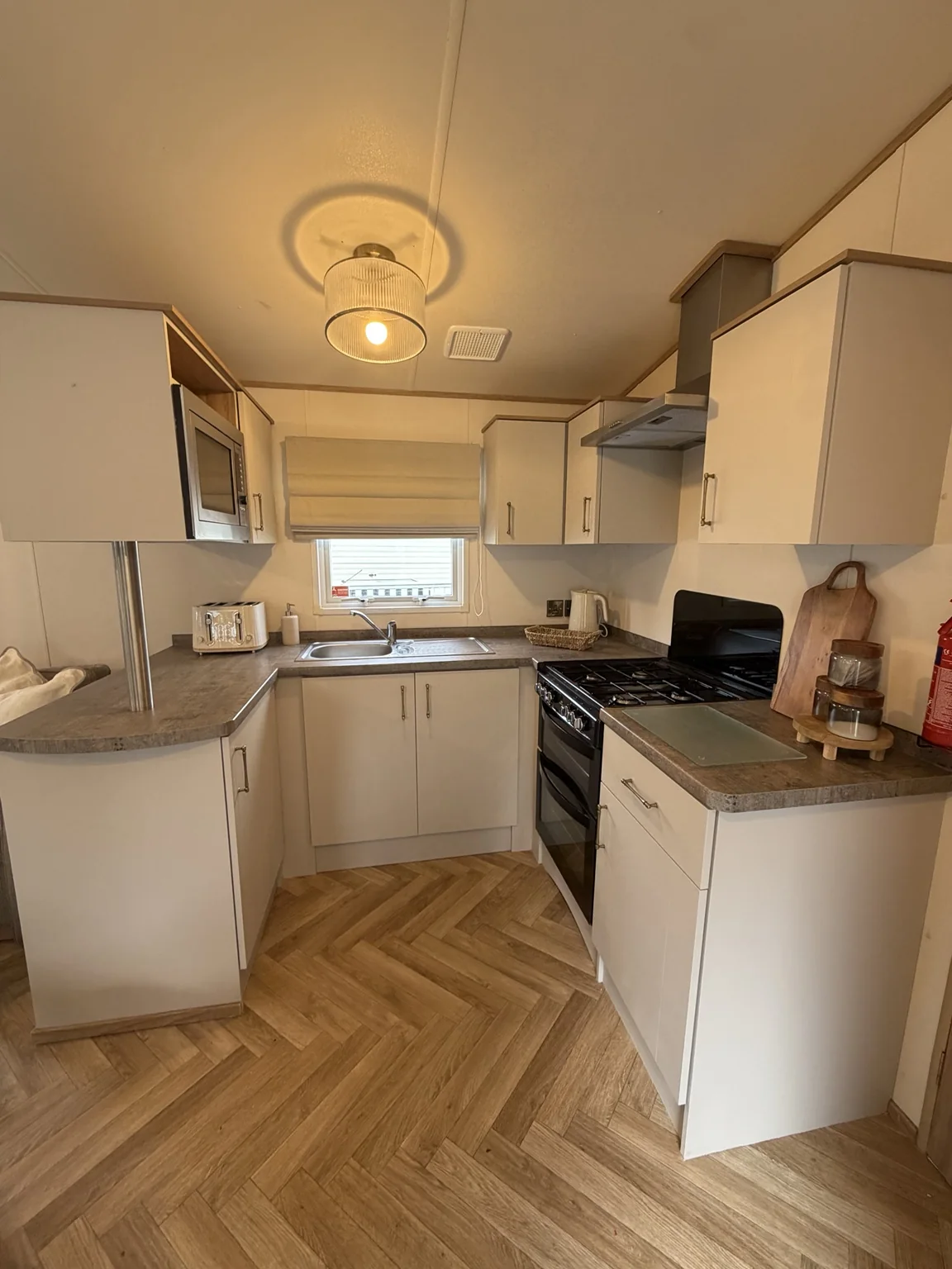 Kitchen with cream cabinetry, gas cooker and sink