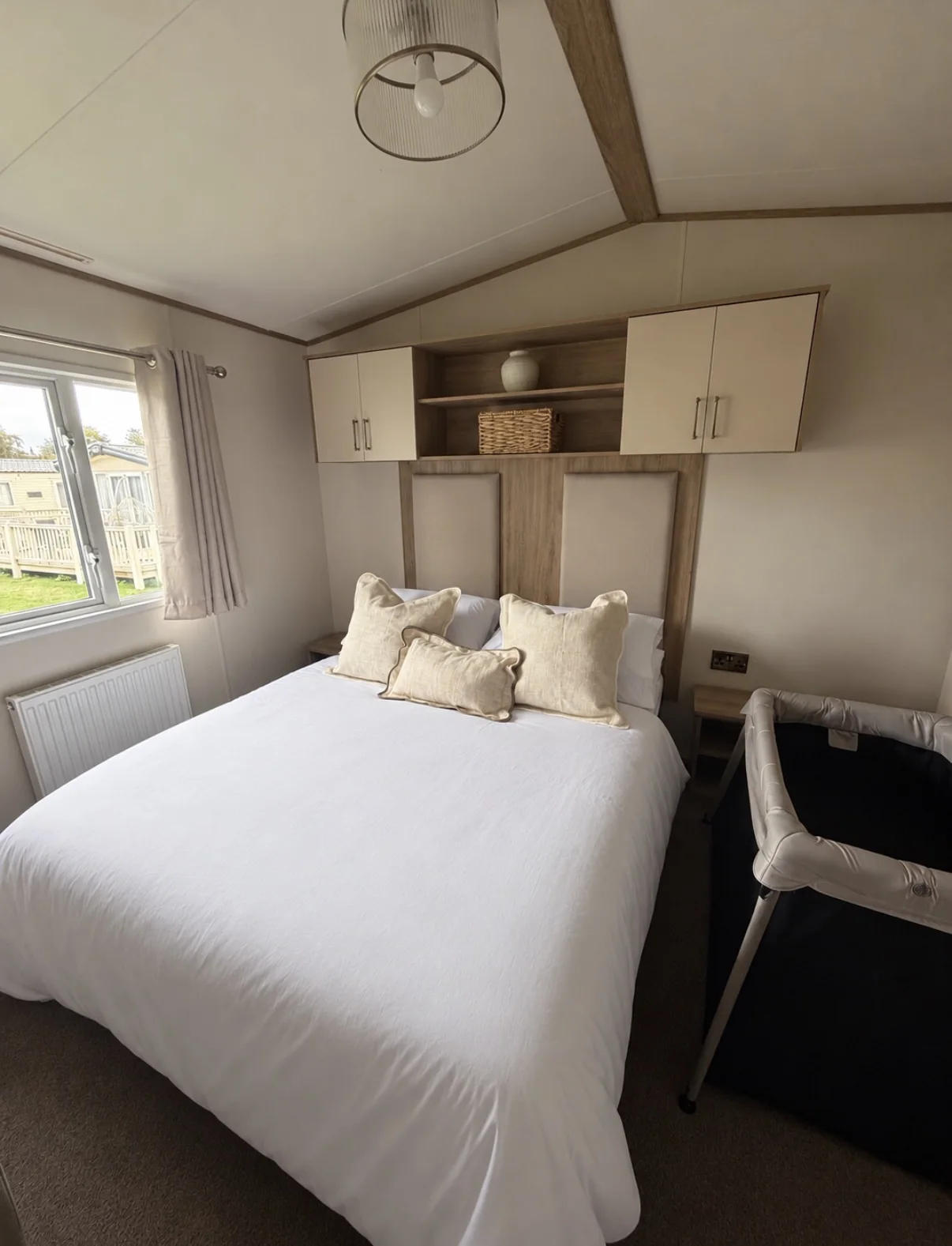 Double bed dressed in crisp white bedding with soft neutral cushions